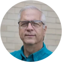 Image of instructor Jay facing front, silver and white hair, wearing glasses and a blue shirt.