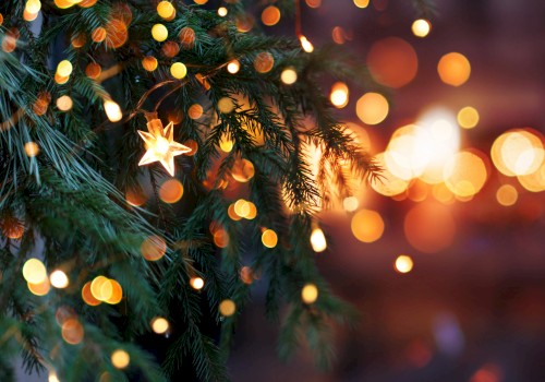A Christmas tree with star-shaped lights, surrounded by a bokeh effect of warm glowing lights, creating a festive ambience.