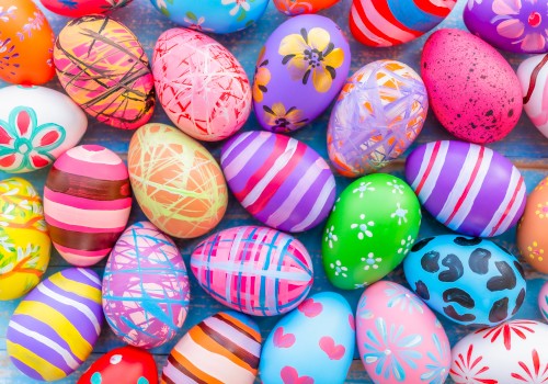 A collection of colorful, intricately decorated Easter eggs in various patterns and designs are spread out on a surface.