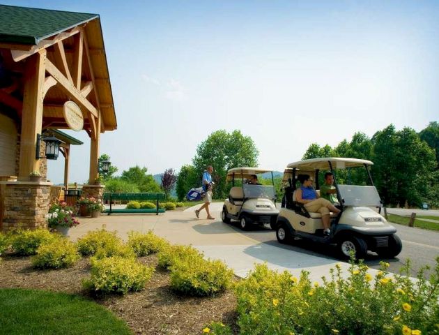The image shows people with golf carts near a building, surrounded by greenery and flowers, creating a peaceful outdoor scene.